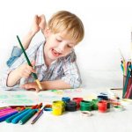 Мальчик рисует кисточкой